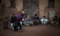 Ein Junge spielt im Kreis der Männer seiner Familie mit Murmeln. Islamabad, Pakistan, Samstag. (Keystone / AP / Emilio Morenatti)