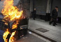 Passanten gehen an einem brennenden Container vorbei, nachdem die spanische Polizei in Bilbao eine Demonstration der baskischen Demokratiepartei aufgelöst hat (Keystone / AP / Alvaro Barrientos)